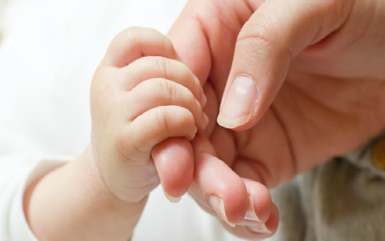 Description_of_image_used_in_impact_of_infant_neglect_mother_hand_holding_baby_hand