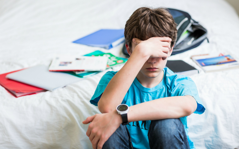 description_of_image_used_in_dealing_with_disruption_older_boy_sitting_alone_in_bedroom_with_his_face_in_his_arms_isopix_rex_shutterstock